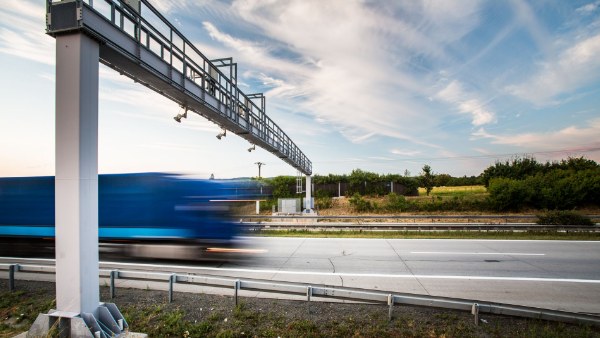 Electronic toll gantry over a highway, with a truck speeding past